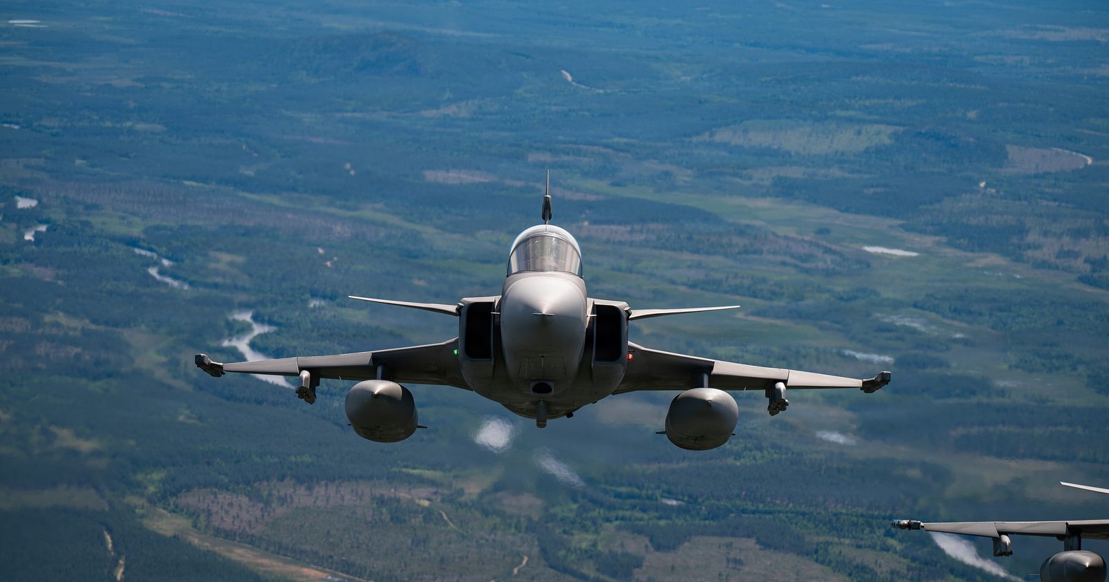 Myśliwiec JAS 39 Gripen w locie w formacji z samolotami sojuszników NATO nad lasami Finlandii